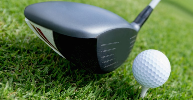 Golf club about to hit a ball