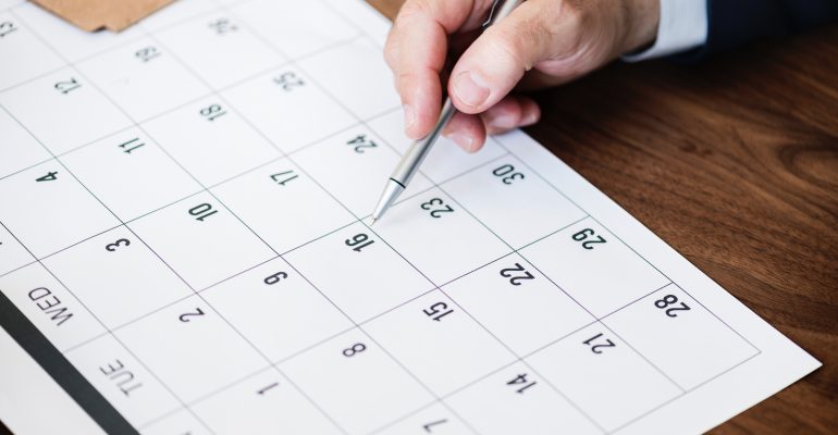Image of a calendar and a man's hand pointing to it